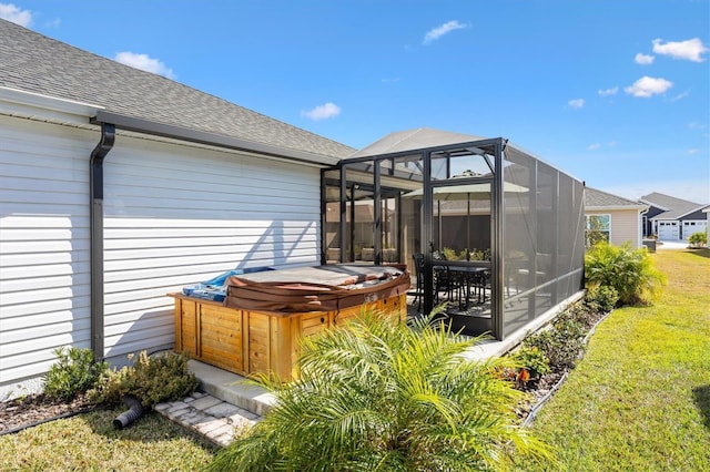 exterior space with glass enclosure, a hot tub, and a lawn