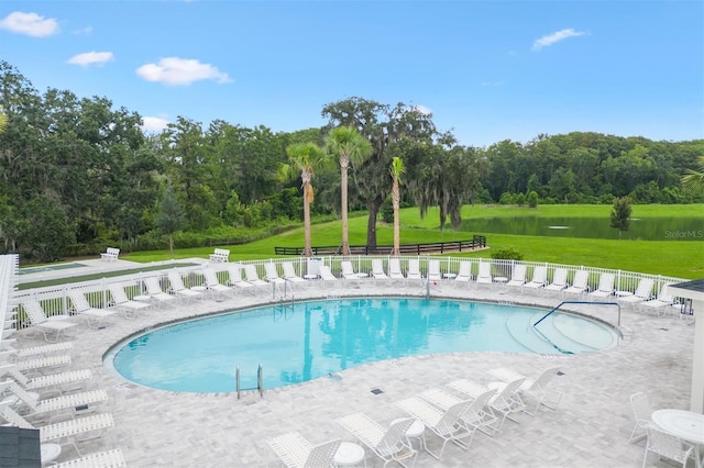 view of pool featuring a patio area, a yard, and a water view