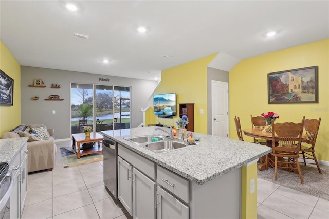 kitchen with appliances with stainless steel finishes, sink, gray cabinetry, light tile patterned floors, and a center island with sink