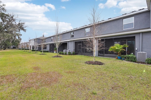 rear view of house featuring a lawn and central air condition unit