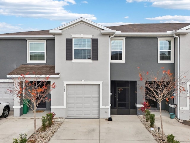 view of front of home featuring concrete driveway, a shingled roof, stucco siding, and a garage