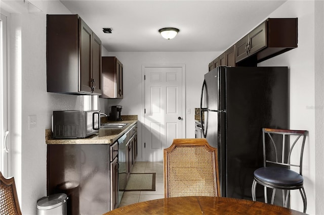 kitchen with sink, dark brown cabinets, black appliances, and light tile patterned flooring