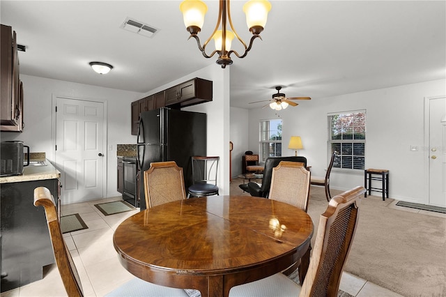 carpeted dining room with ceiling fan with notable chandelier