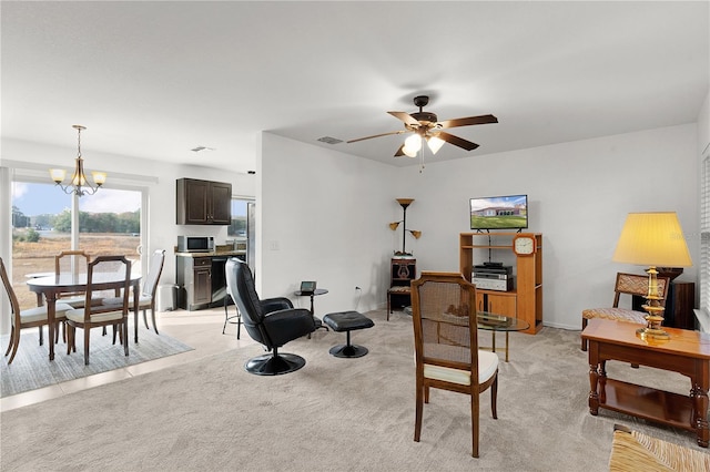 living room featuring ceiling fan with notable chandelier and light carpet