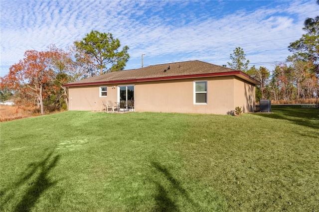 rear view of house with central AC and a yard