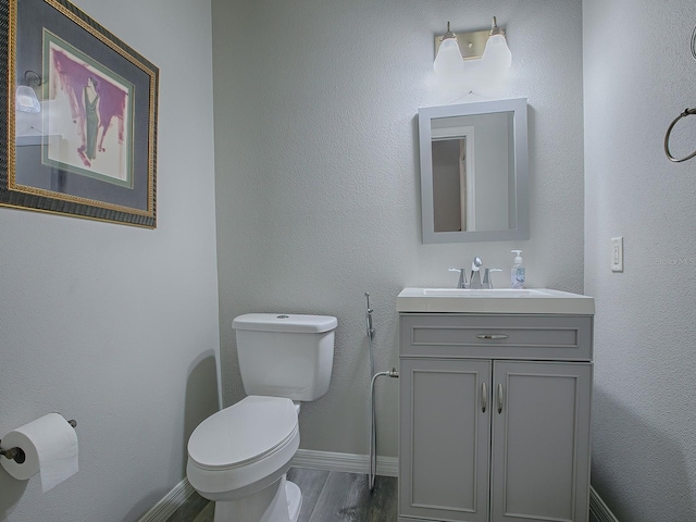 bathroom featuring toilet, vanity, and hardwood / wood-style flooring