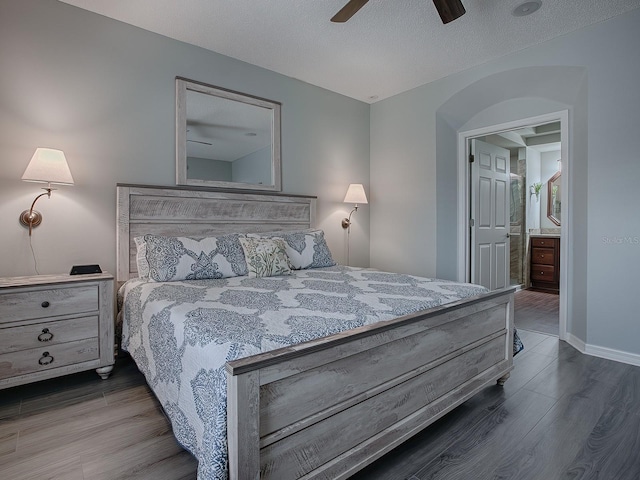 bedroom with a textured ceiling, ceiling fan, connected bathroom, and hardwood / wood-style floors