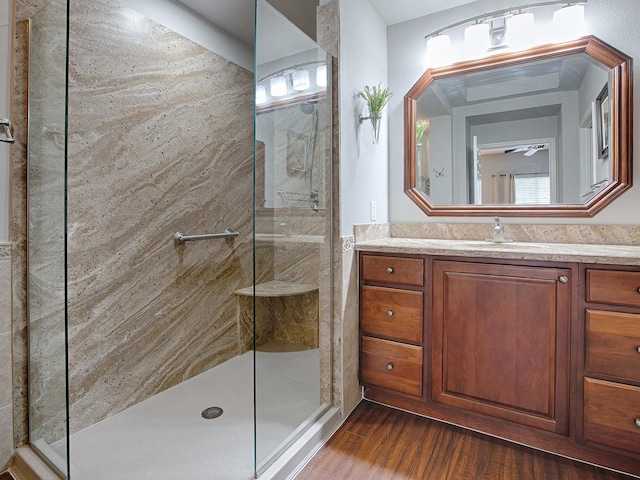 bathroom featuring ceiling fan, vanity, wood-type flooring, and tiled shower