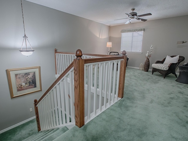 stairway with ceiling fan, a textured ceiling, and carpet flooring