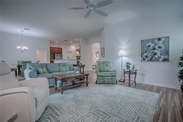 living room featuring lofted ceiling, ceiling fan with notable chandelier, and wood-type flooring