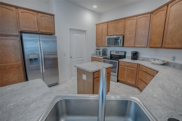 kitchen featuring sink, light tile patterned floors, stainless steel appliances, and a kitchen island