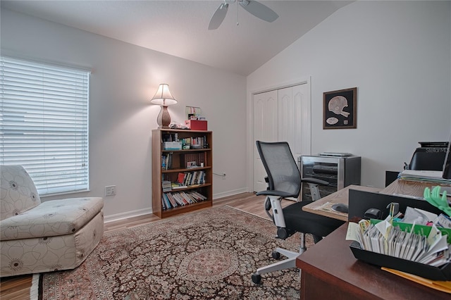 home office featuring ceiling fan, lofted ceiling, wood-type flooring, and a healthy amount of sunlight