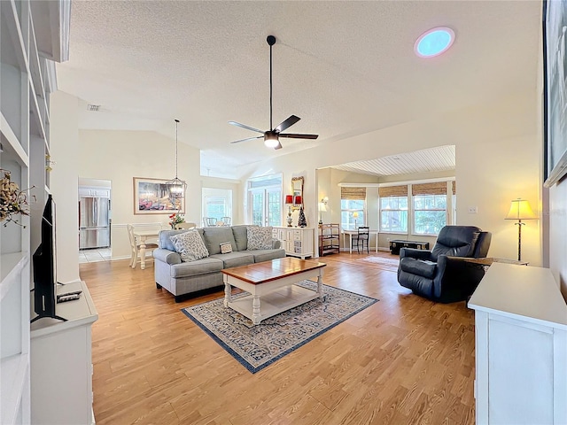 living room with lofted ceiling, a textured ceiling, ceiling fan, and light wood-type flooring