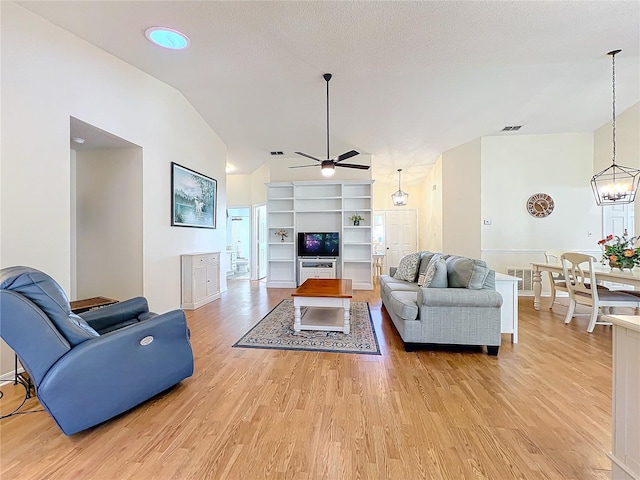 living room featuring ceiling fan with notable chandelier, a textured ceiling, vaulted ceiling, and light hardwood / wood-style flooring