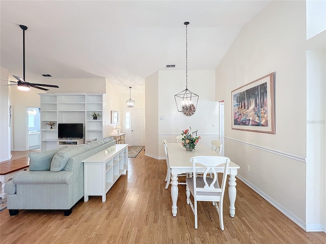 dining area with lofted ceiling, ceiling fan with notable chandelier, and light wood-type flooring