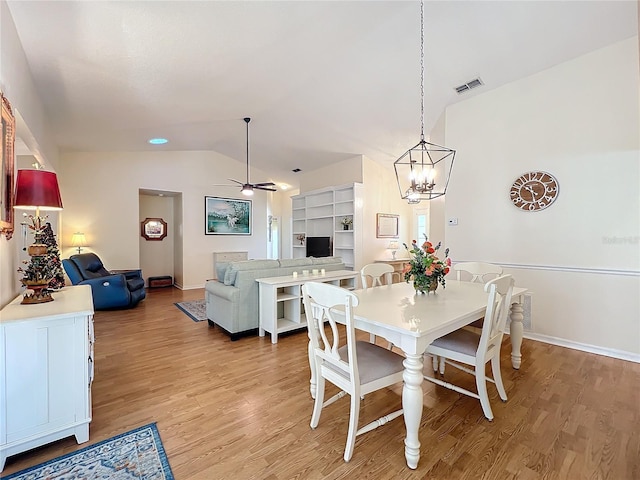 dining space featuring ceiling fan with notable chandelier, light hardwood / wood-style floors, and lofted ceiling