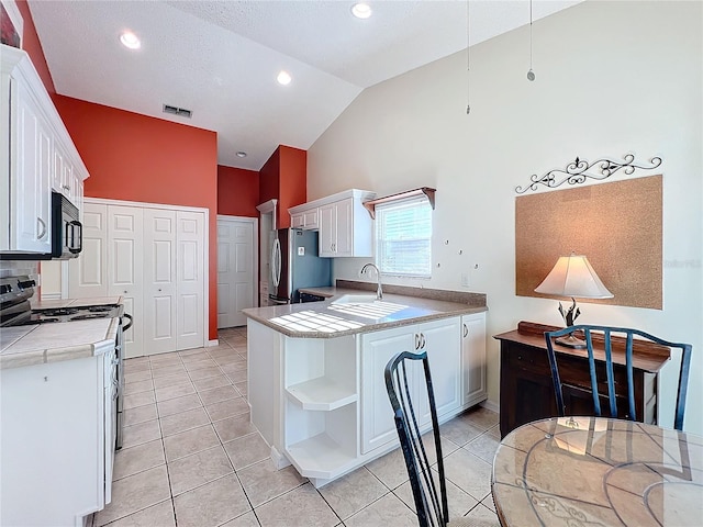 kitchen with white cabinets, vaulted ceiling, appliances with stainless steel finishes, and kitchen peninsula