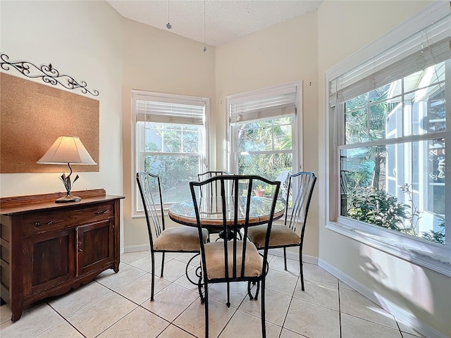 dining space with a textured ceiling, light tile patterned flooring, and a healthy amount of sunlight