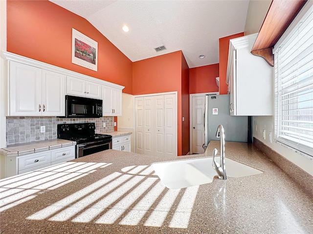 kitchen featuring black appliances, tasteful backsplash, lofted ceiling, white cabinets, and sink