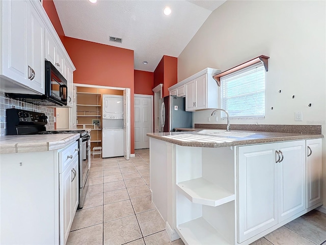 kitchen with black appliances, white cabinetry, lofted ceiling, and stacked washer and dryer