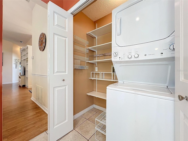 washroom featuring stacked washing maching and dryer and light tile patterned flooring