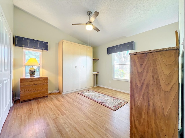 bedroom with vaulted ceiling, a closet, ceiling fan, multiple windows, and hardwood / wood-style flooring