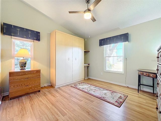 bedroom featuring a textured ceiling, a closet, lofted ceiling, light wood-type flooring, and ceiling fan