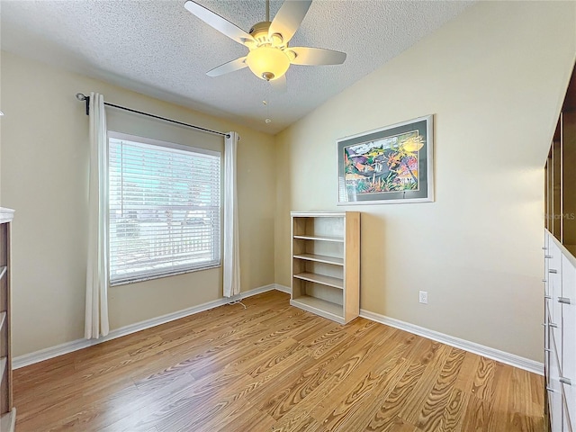 unfurnished bedroom with vaulted ceiling, a textured ceiling, ceiling fan, and light hardwood / wood-style flooring