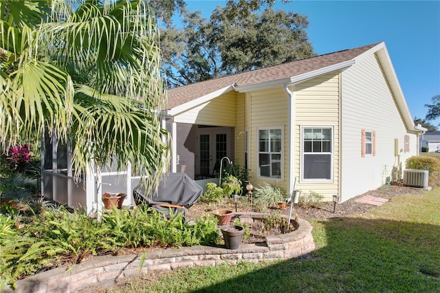 rear view of property featuring a lawn and central AC unit