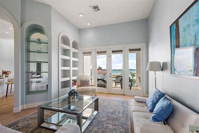 tiled living room featuring built in features and a water view