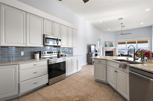 kitchen featuring stainless steel appliances, light tile patterned floors, ceiling fan, sink, and white cabinetry