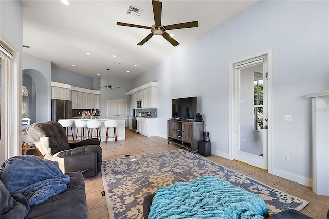 tiled living room with a high ceiling and ceiling fan