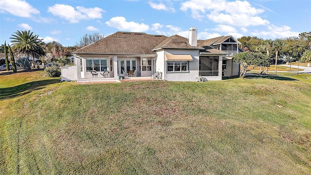 back of house featuring a patio, a sunroom, and a lawn