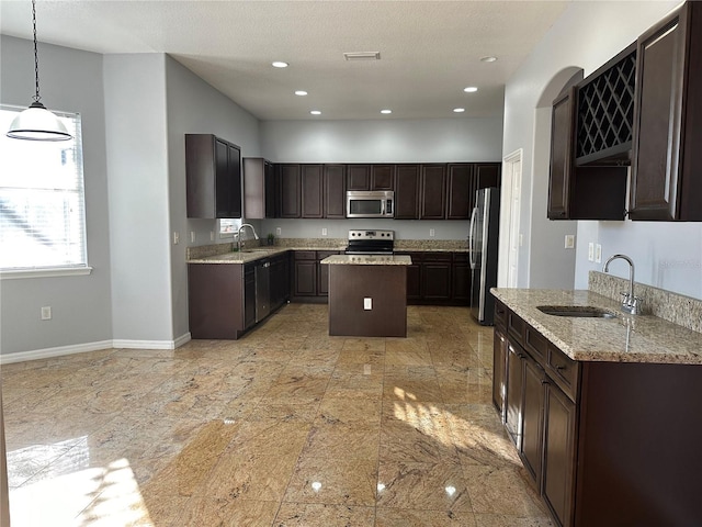 kitchen featuring sink, stainless steel appliances, dark brown cabinets, and hanging light fixtures