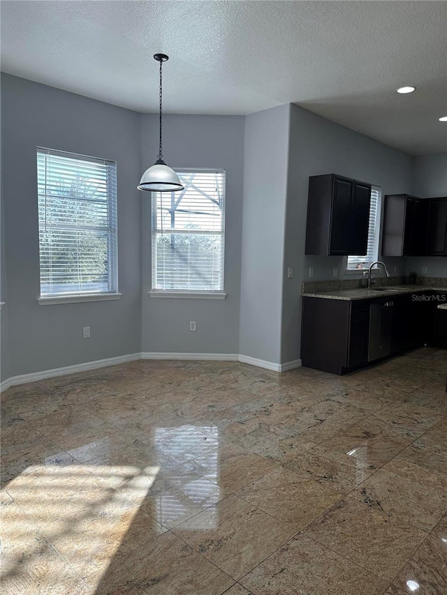 kitchen featuring a textured ceiling, hanging light fixtures, and sink