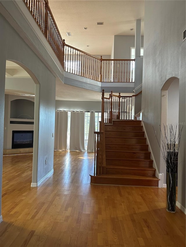 staircase featuring wood-type flooring and a high ceiling