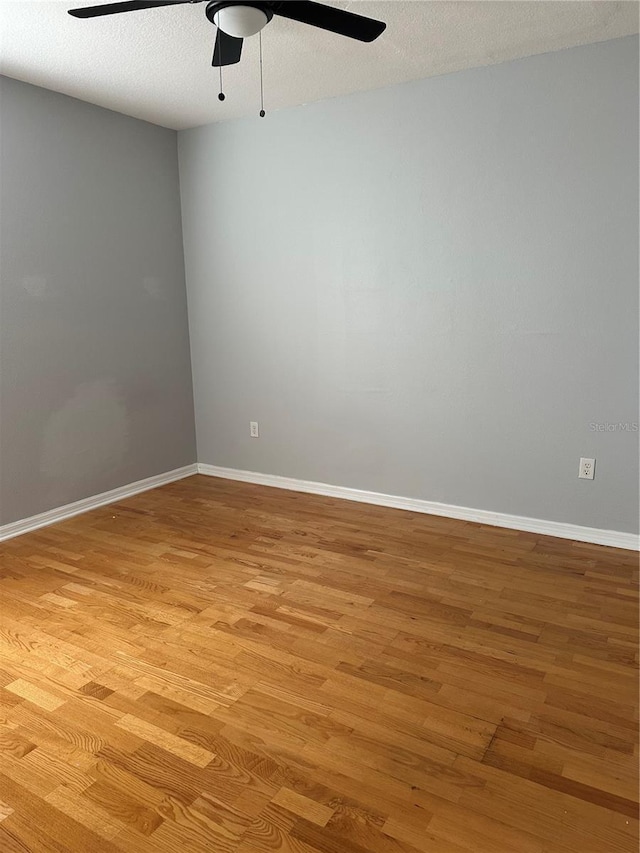 empty room featuring a textured ceiling, light wood-type flooring, and ceiling fan