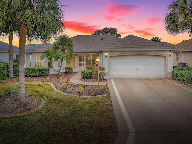 ranch-style home with central air condition unit, a yard, and a garage