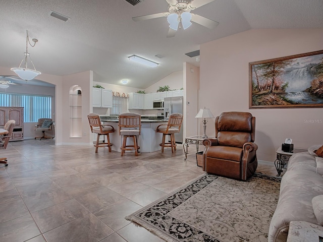 tiled living room with vaulted ceiling, ceiling fan, and a textured ceiling