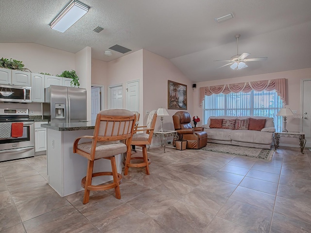 kitchen featuring white cabinets, stainless steel appliances, and lofted ceiling