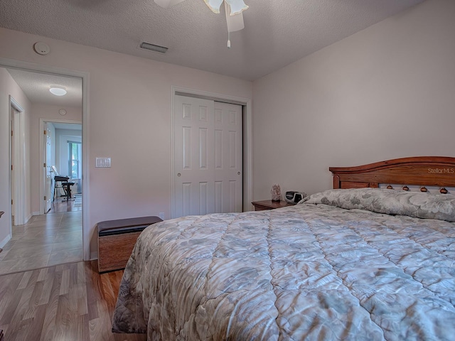 bedroom featuring light wood-type flooring, ceiling fan, a textured ceiling, and a closet