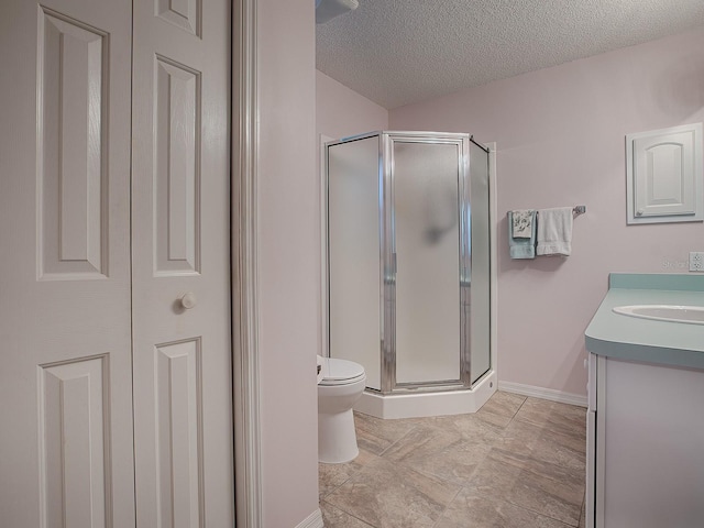 bathroom featuring a textured ceiling, toilet, a shower with shower door, and vanity