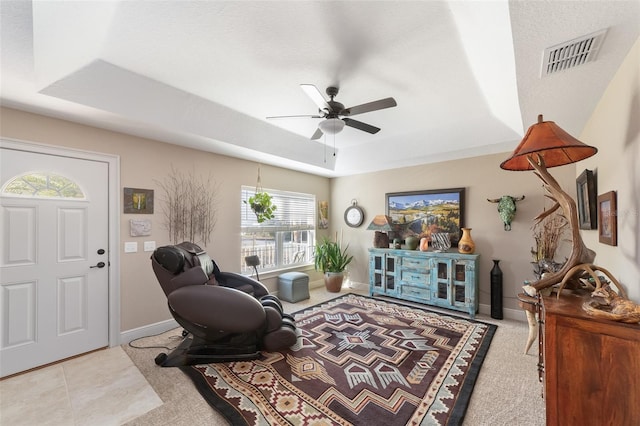 living room with ceiling fan and a tray ceiling