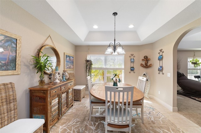 carpeted dining room with a raised ceiling, a wealth of natural light, and a chandelier