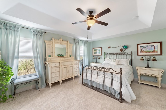 bedroom with multiple windows, a raised ceiling, and ceiling fan