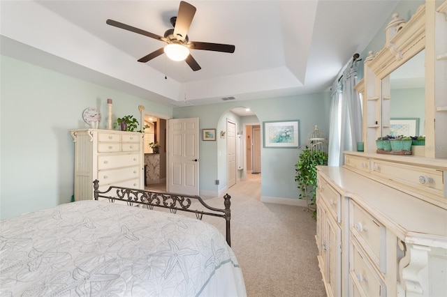 carpeted bedroom with connected bathroom, ceiling fan, and a tray ceiling