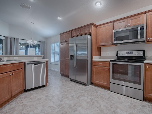 kitchen featuring pendant lighting, appliances with stainless steel finishes, lofted ceiling, sink, and a notable chandelier