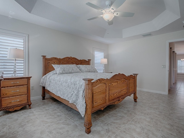 bedroom with ceiling fan and a tray ceiling