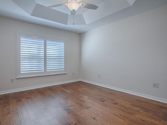 spare room with ceiling fan, a tray ceiling, and hardwood / wood-style floors