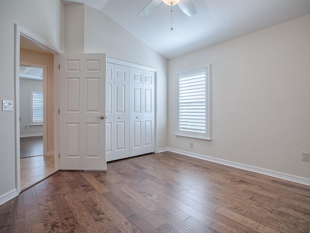 unfurnished bedroom featuring ceiling fan, wood-type flooring, a closet, and lofted ceiling